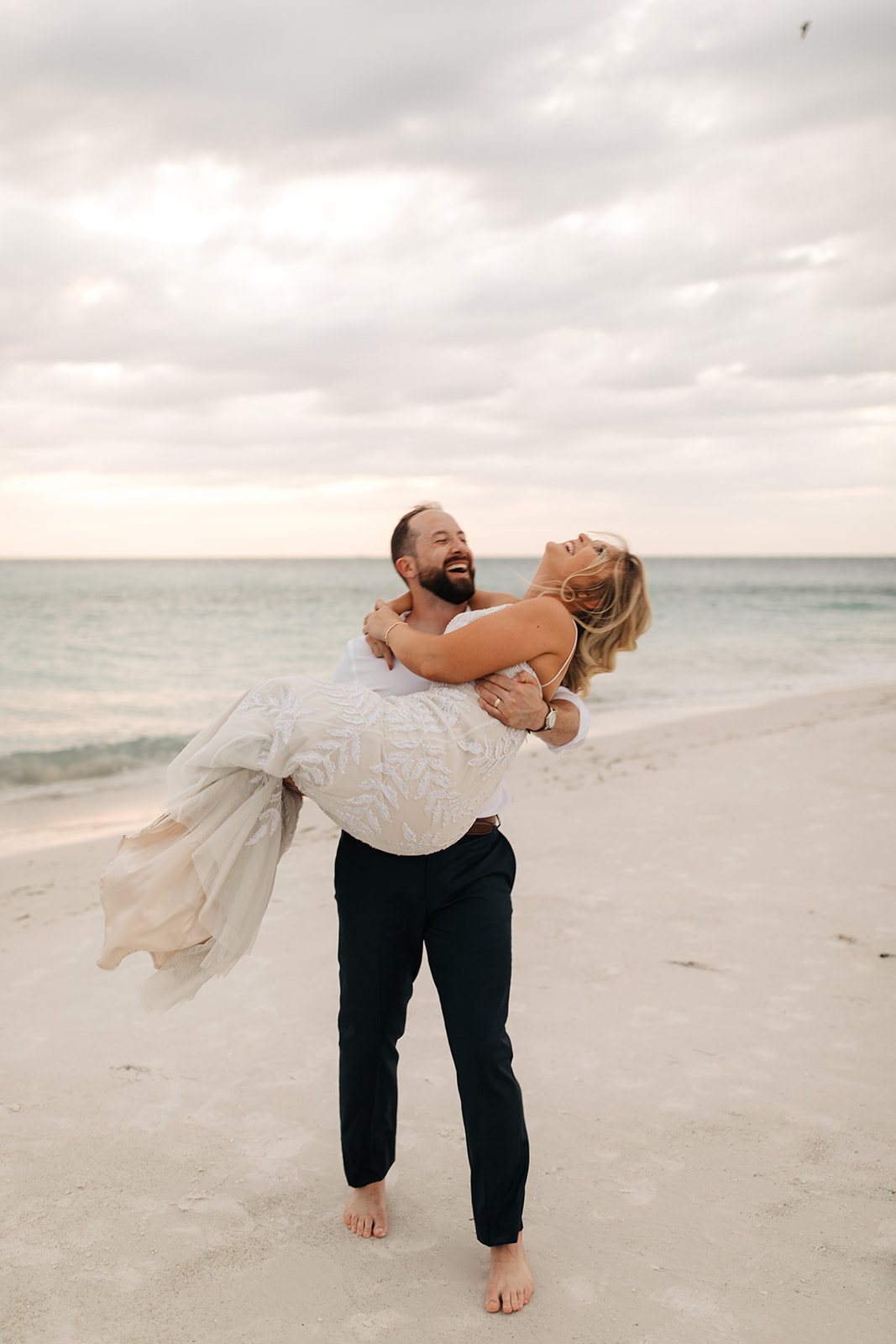 the bride and groom laugh on the beach at Anna Maria Island in Florida