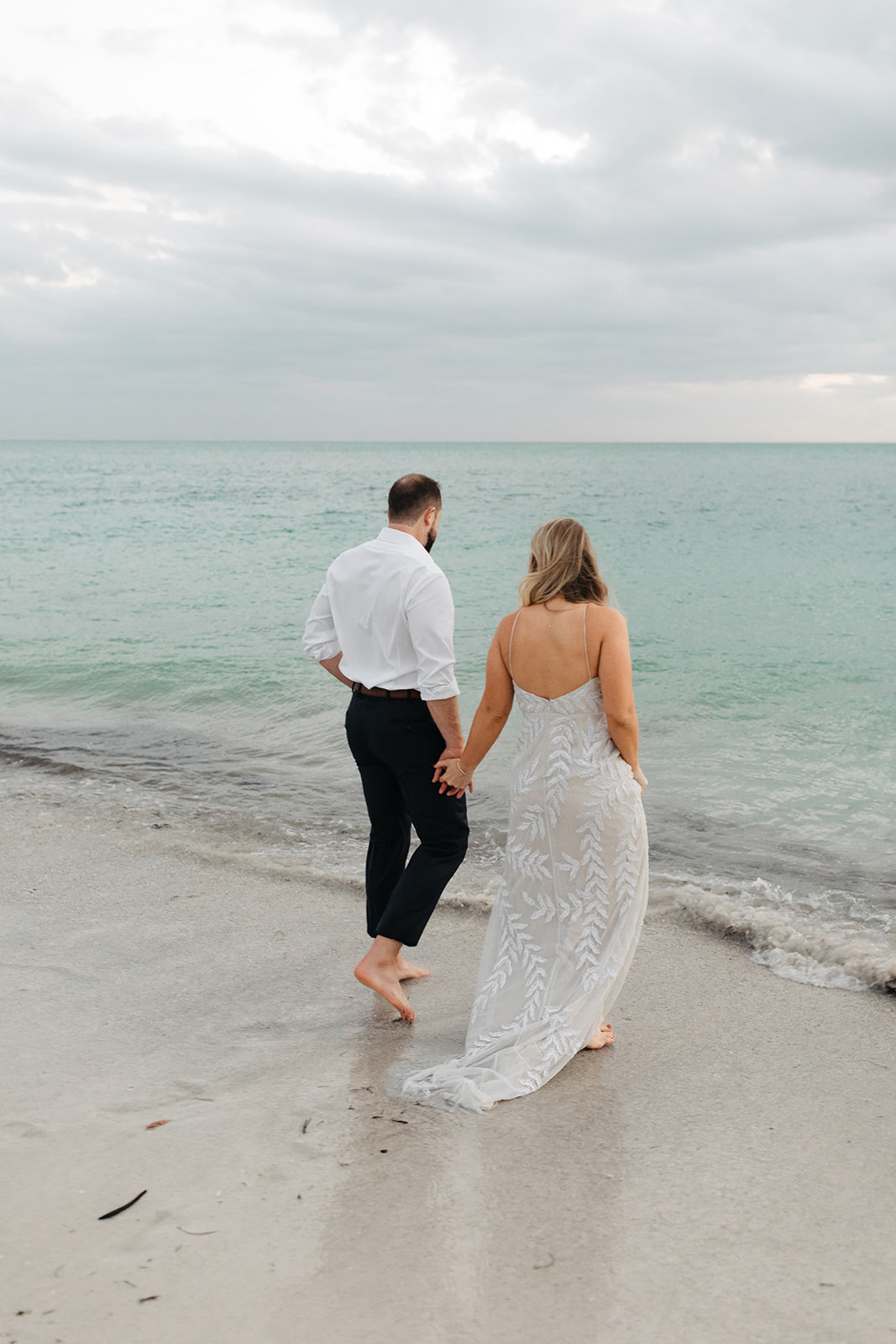 the bride and groom walking into the water at Anna Maria Island in Florida