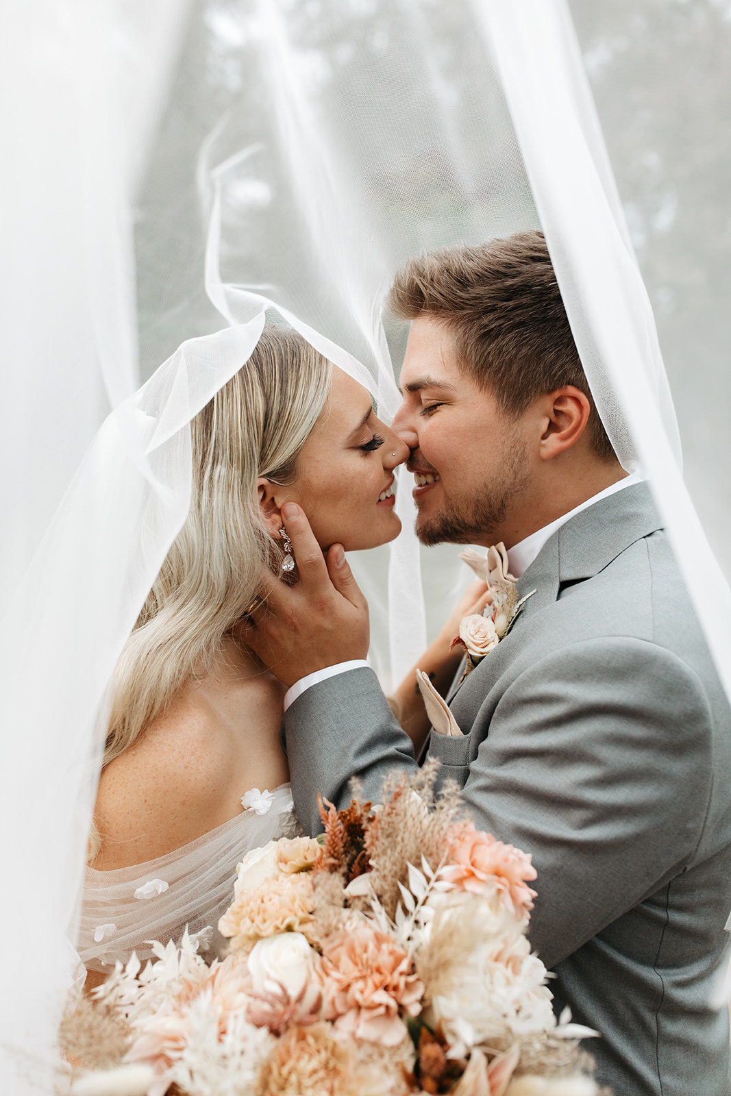 the couple kissing underneath the veil