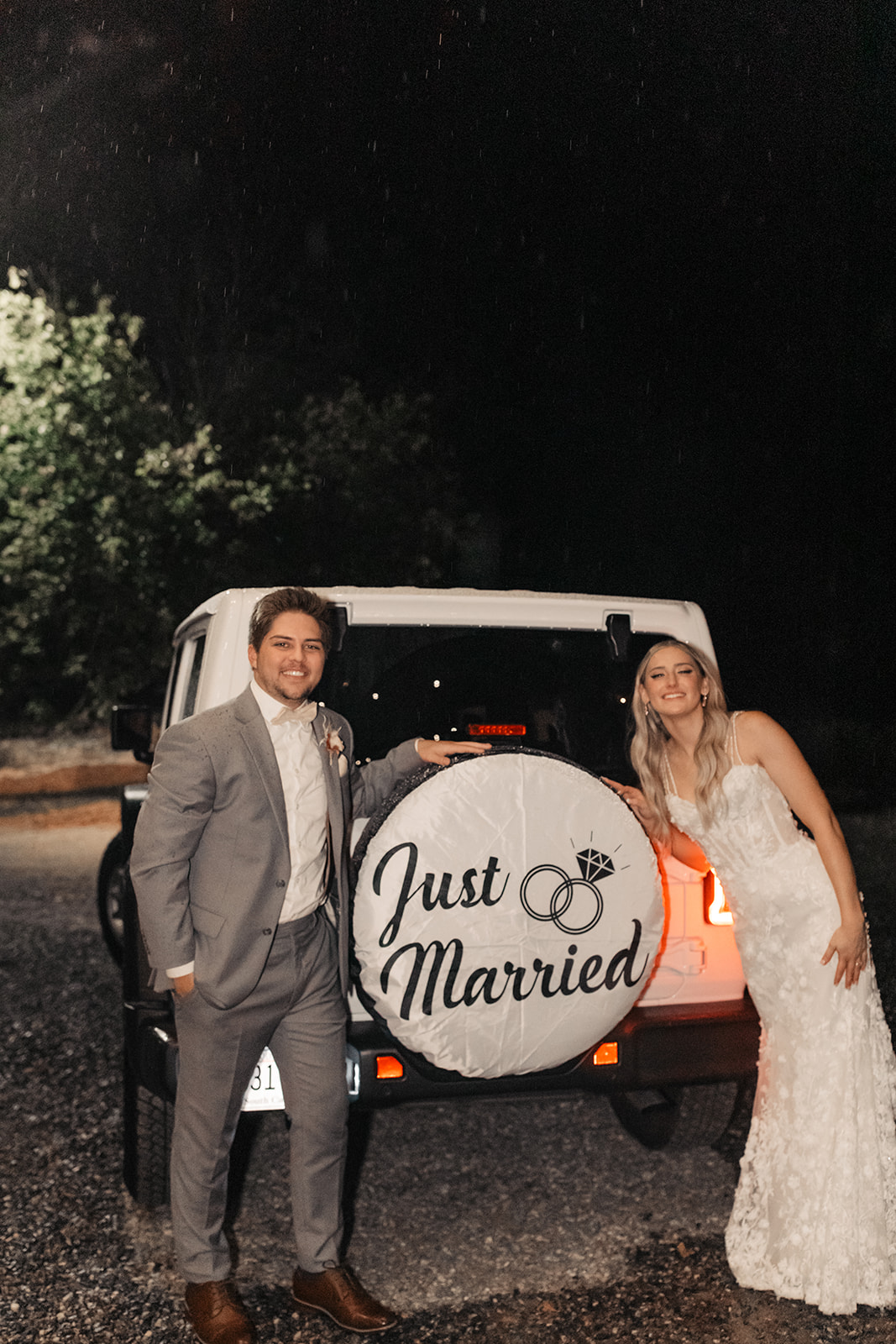 the couple standing next to their just married car