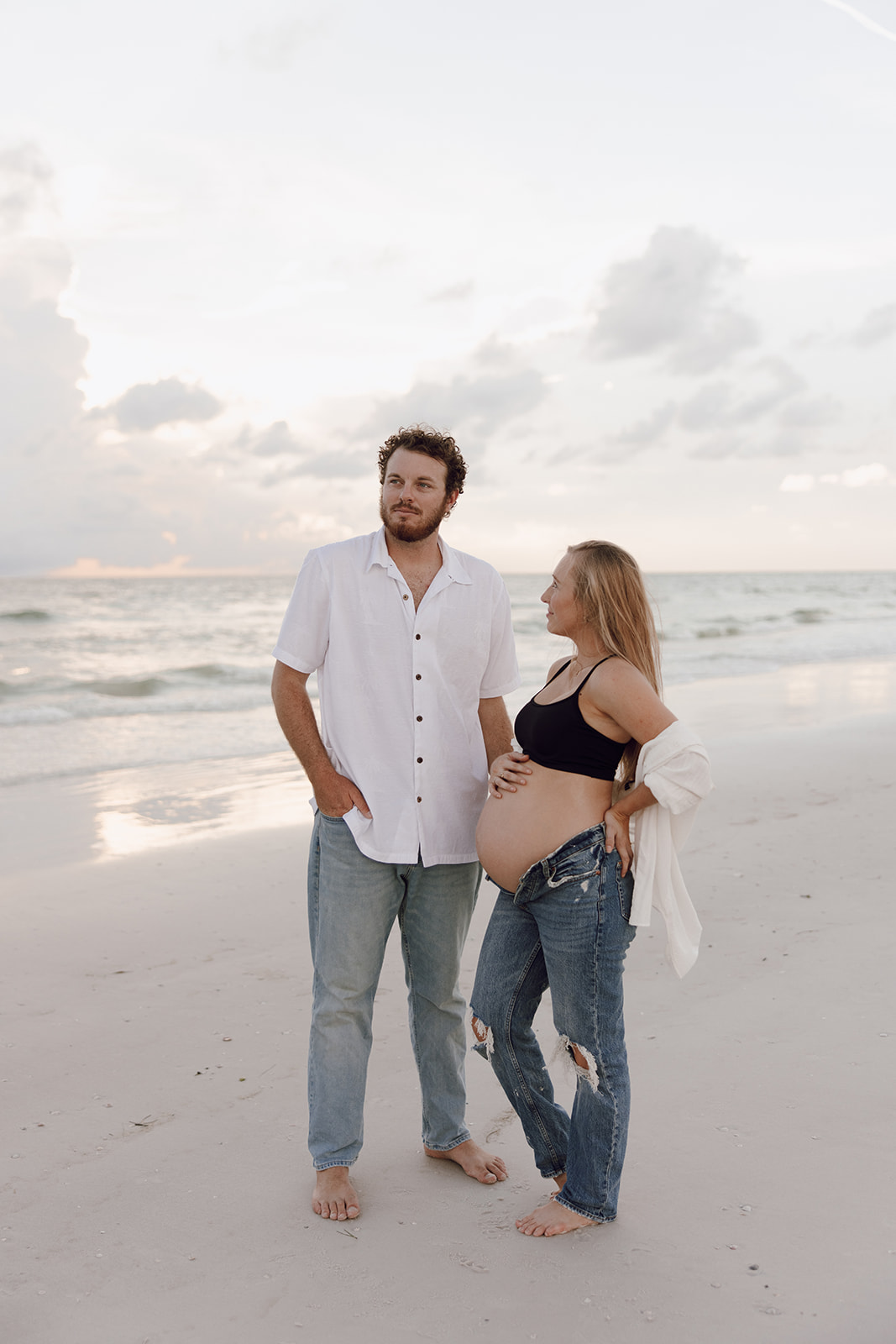 the couple standing together on the beach for their couple photo maternity session