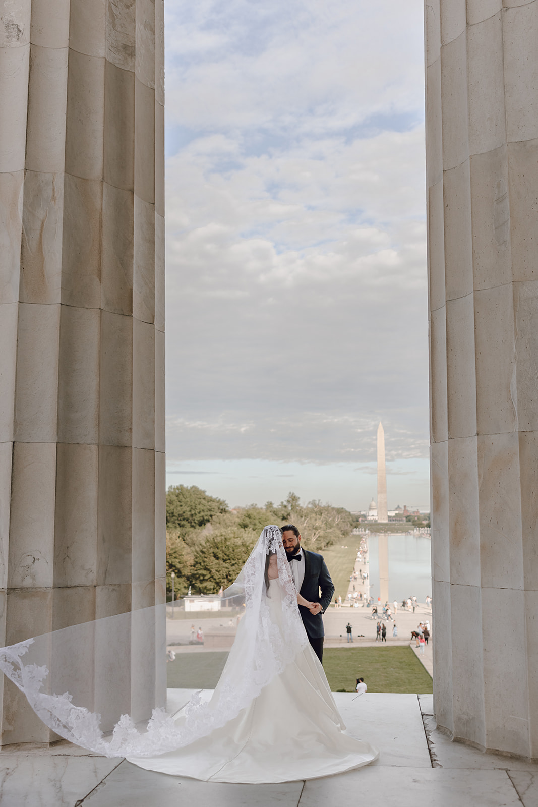 the bride and groom standing together at Washington DC with her veil flowing in the wind