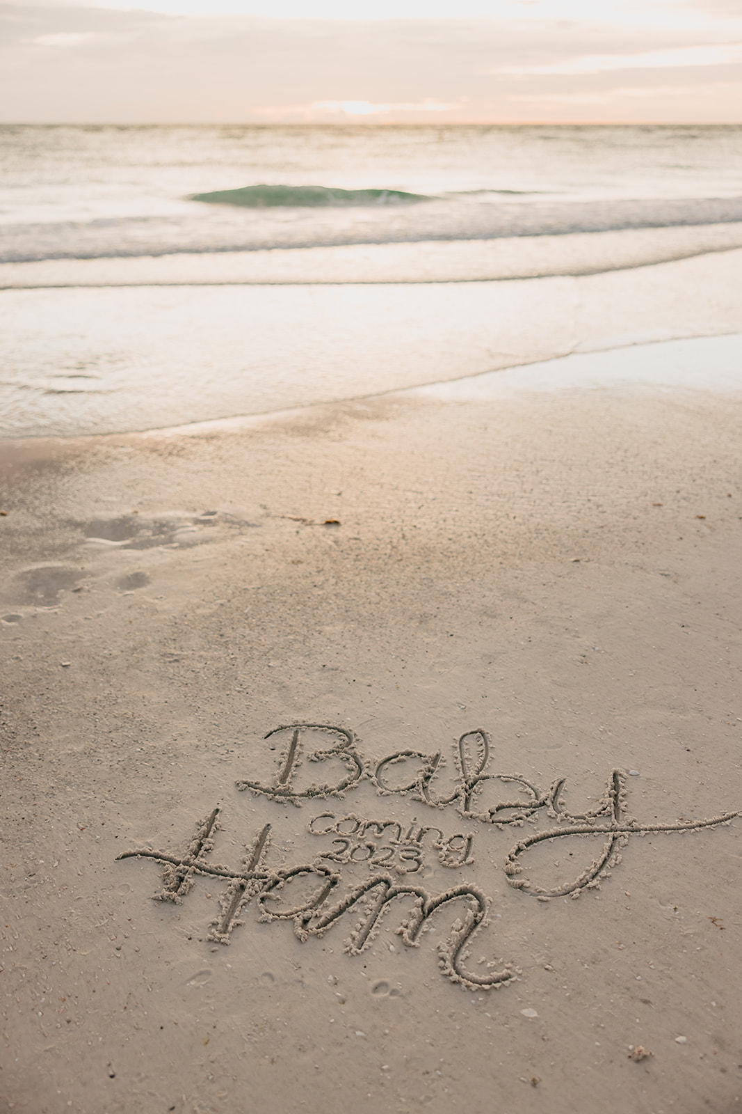 a message written in the sand announcing a baby as an idea for beach photoshoot