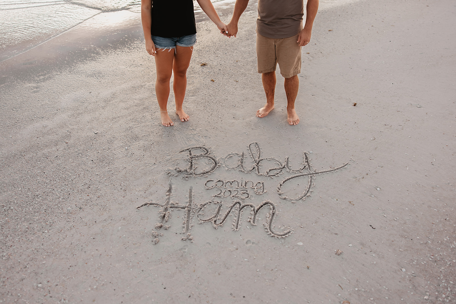 the couple standing over the message written in the sand
