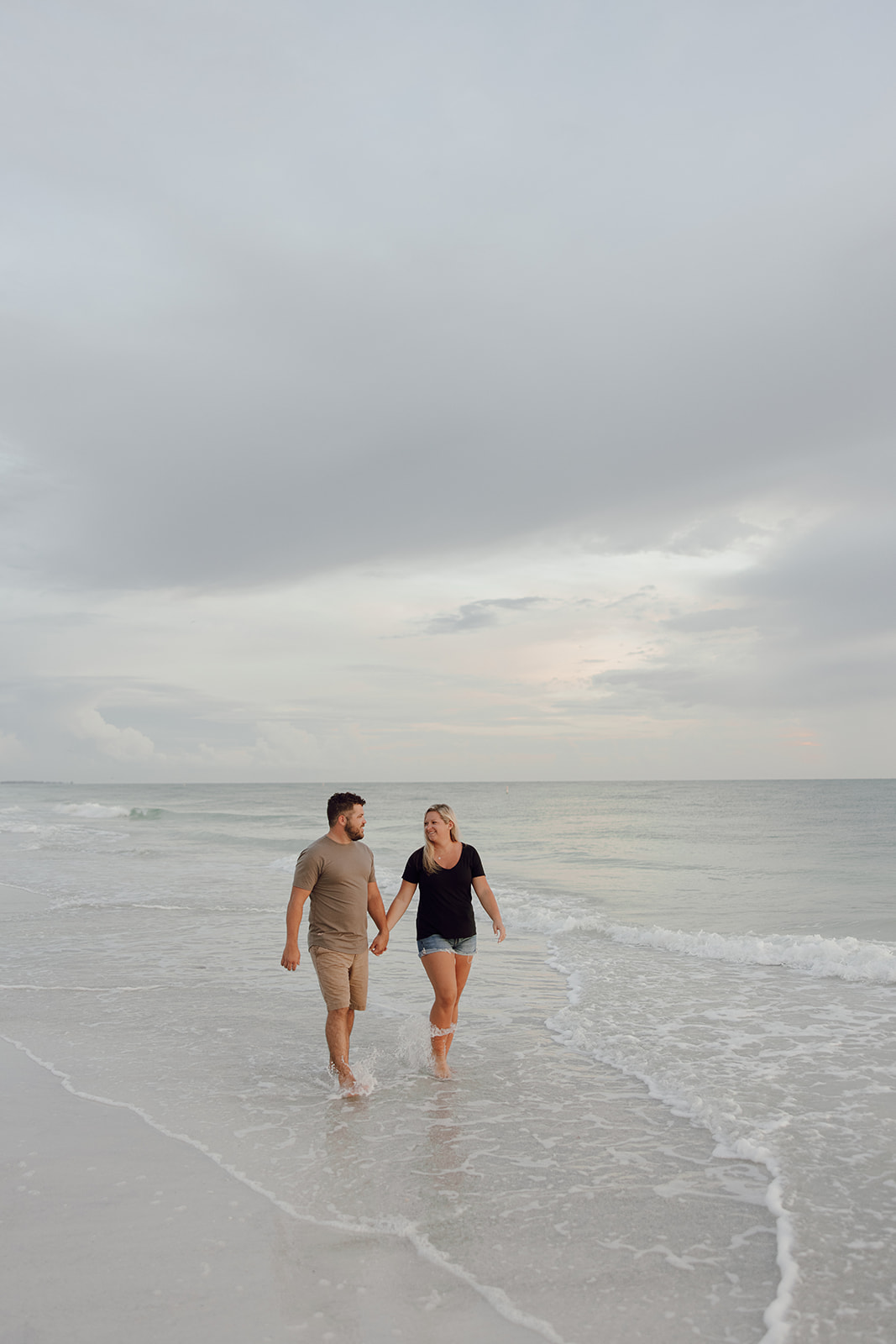 the couple holding hands as they walk down the beach as an idea for beach photoshoot
