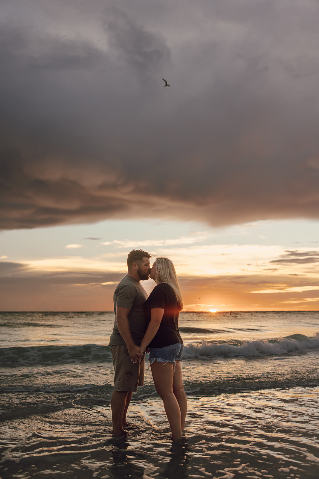 the couple kissing at the beach during sunset