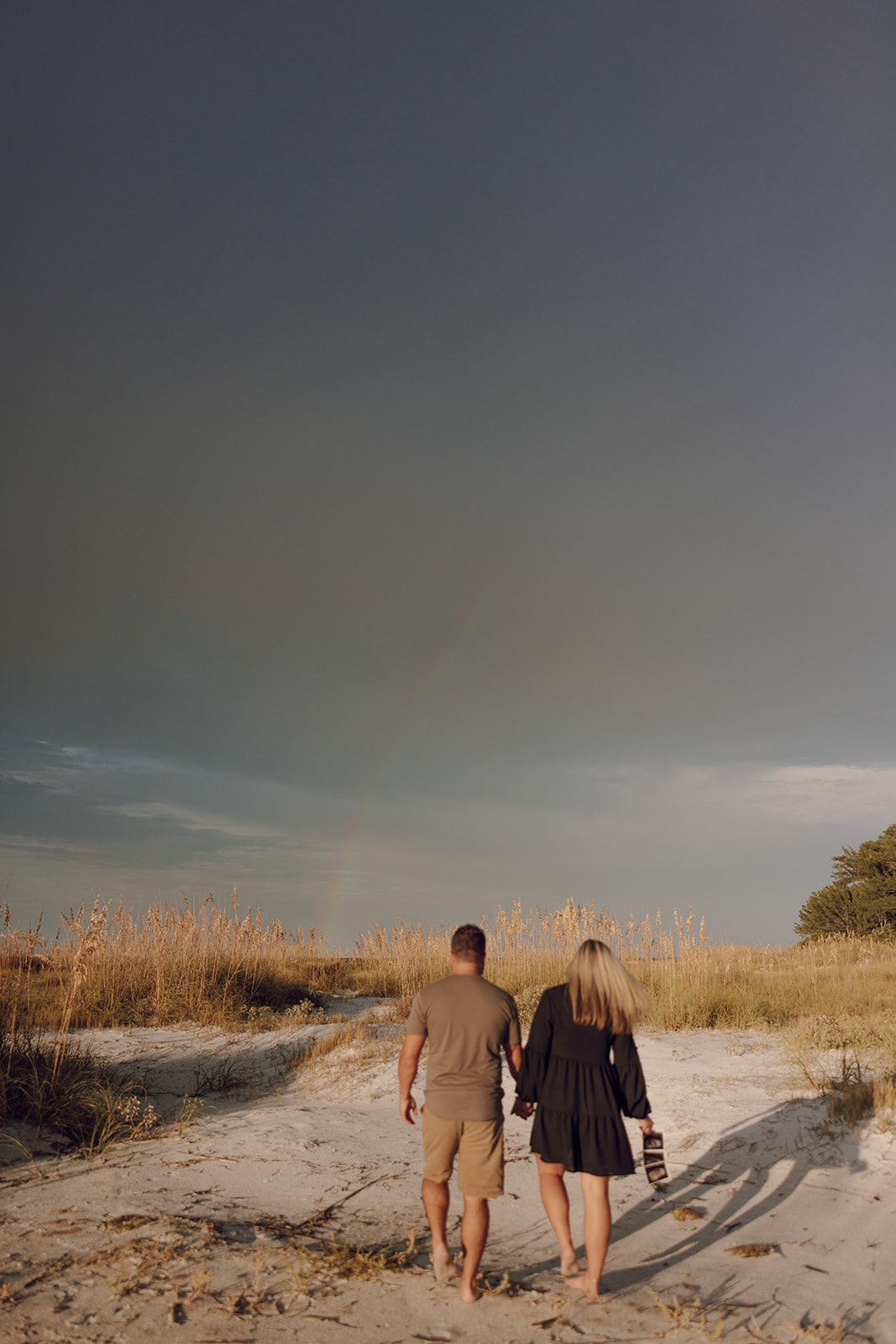the couple walking towards the rainbow