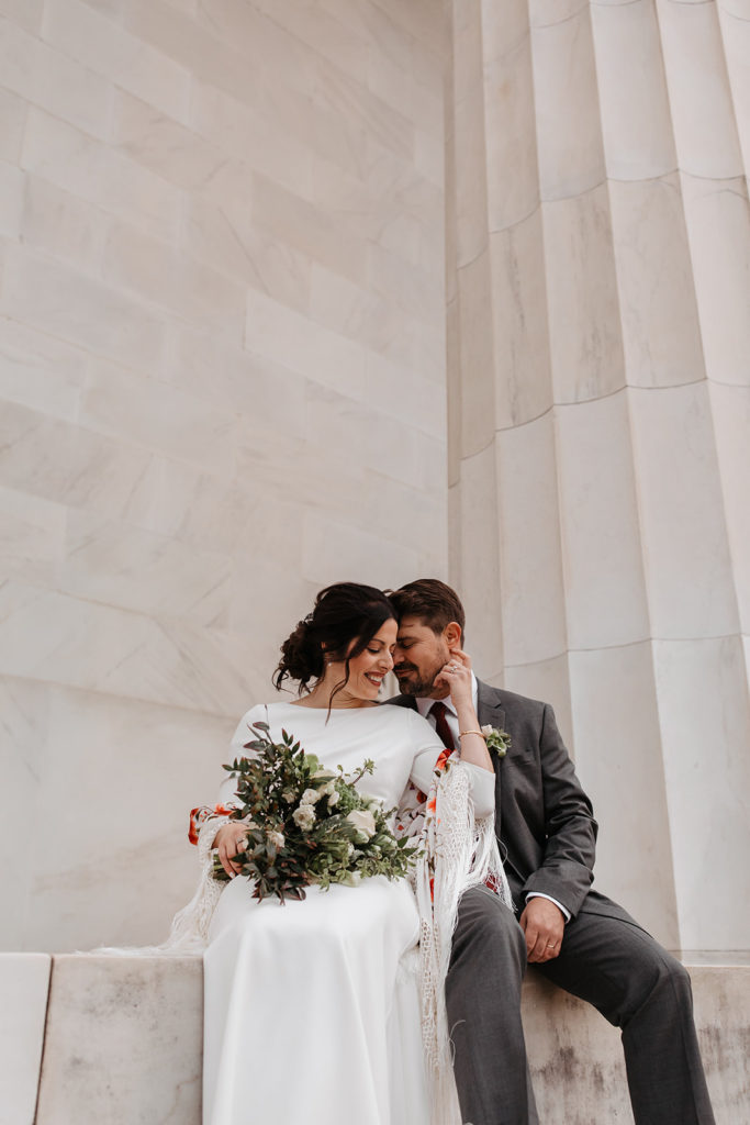 the couple sitting down on the Lincoln Memorial for wedding photos