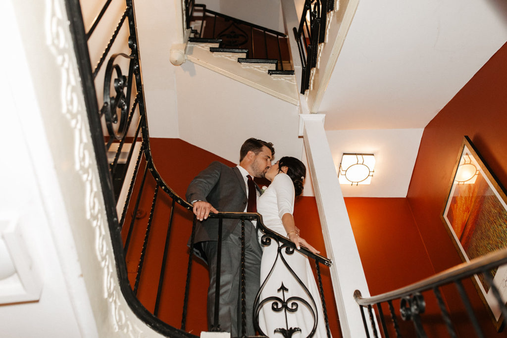 the couple kissing on the staircase at the hotel of their wedding venue