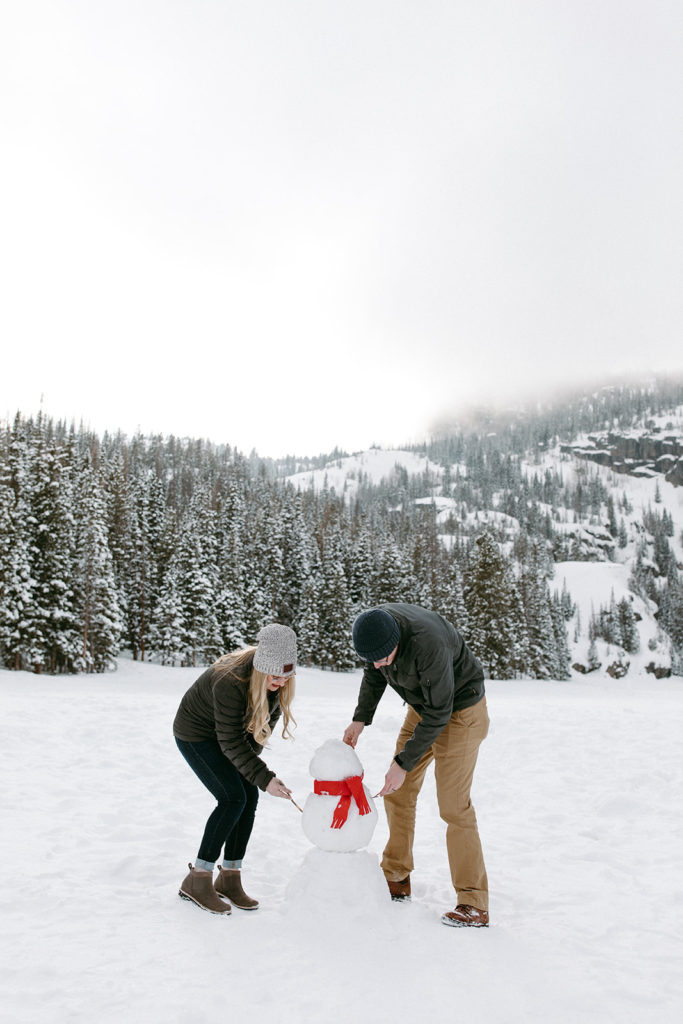 the couple building a snowman during their honeymoon session