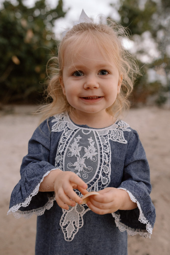 little girl at the beach collecting shells during beach family photos