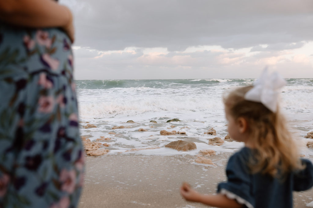 the little girl and mom standing on the beach together
