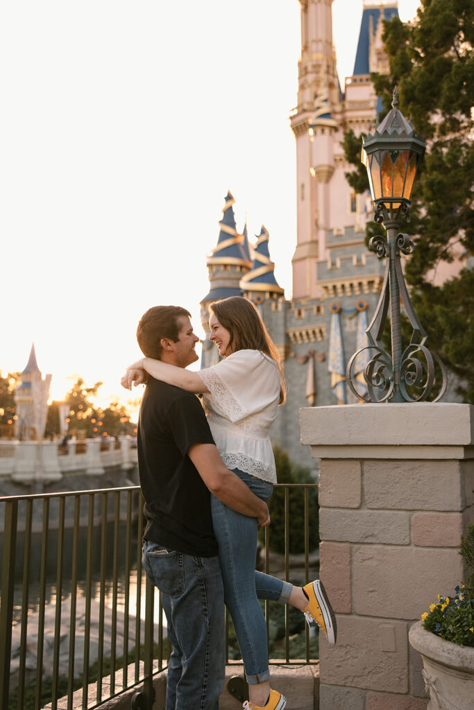 the fiance lifting her up for engagement photos at the Magic Kingdom