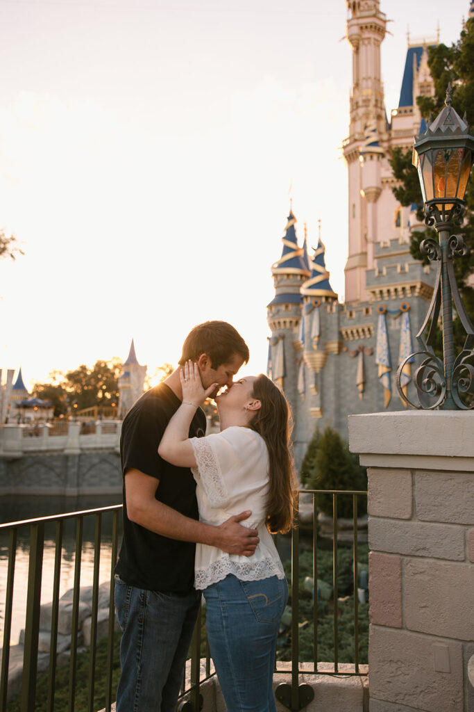 the engagement couple leaning in for a kiss at the Cinderella Castle