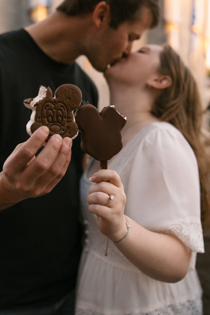 the engaged couple kissing at Walt Disney World while holding Mickey Ice Cream