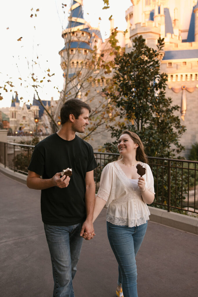 the couple holding hands and walking along the path with their ice cream at Walt Disney World
