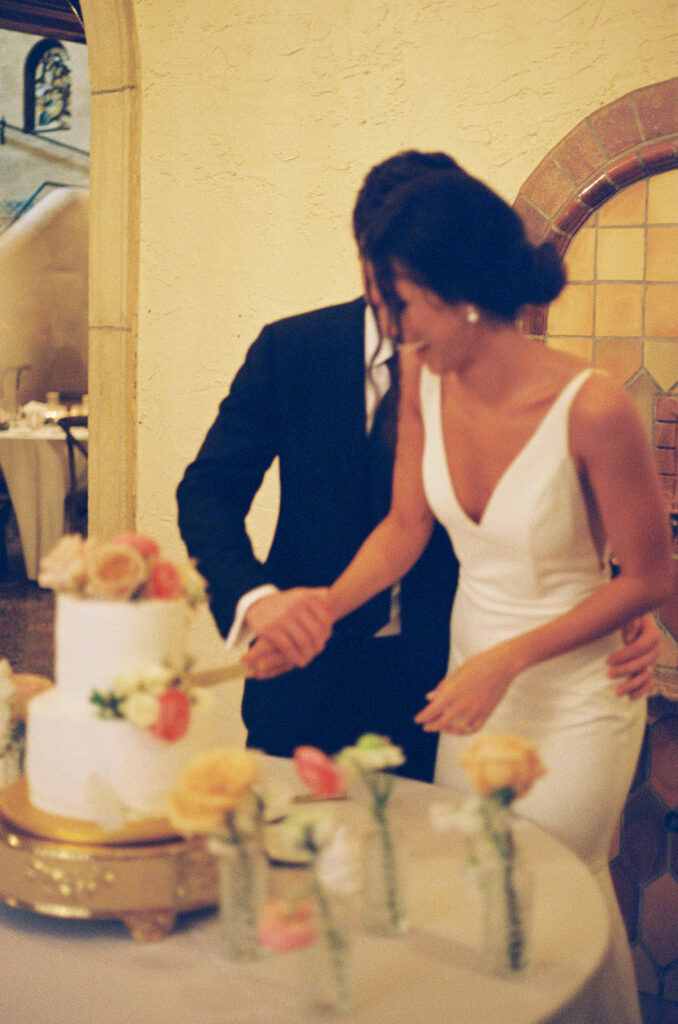 the bride and groom cutting the cake at their wedding reception