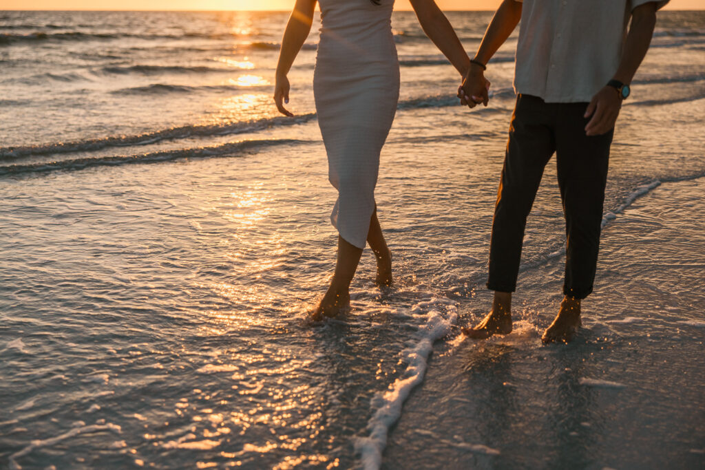 the engaged couple walking hand in hand down the beach in Tampa