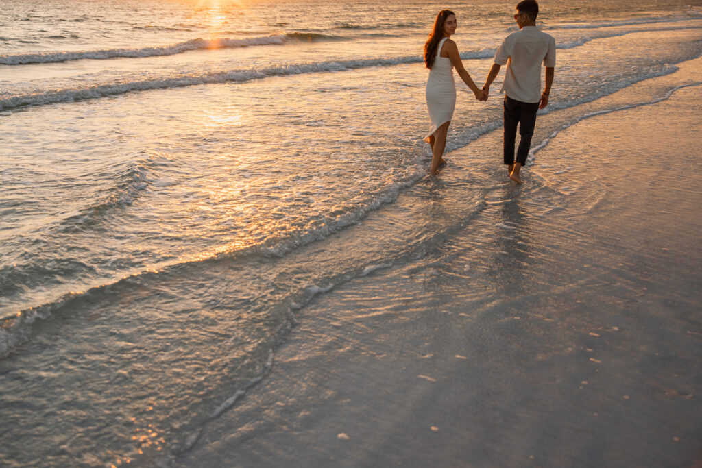 the engaged couple walking along the beach in Tampa, Florida during photoshoot