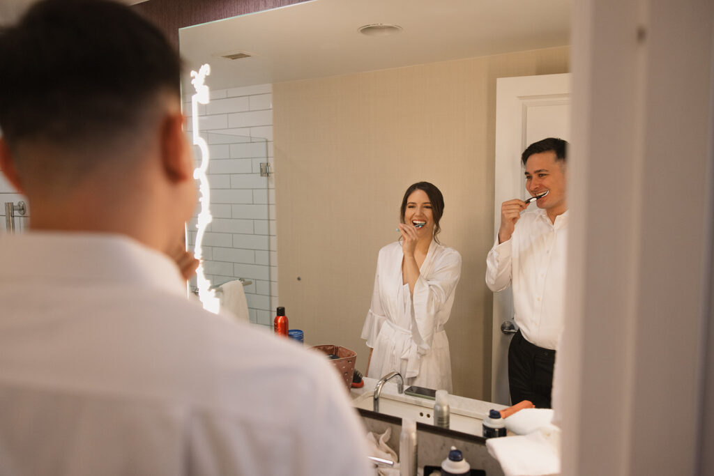 the bride and groom brushing their teeth together before their destination wedding