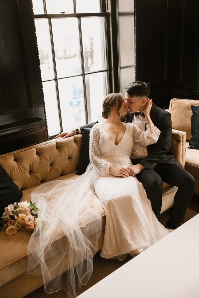 the bride and groom kissing at their wedding venue on the couch