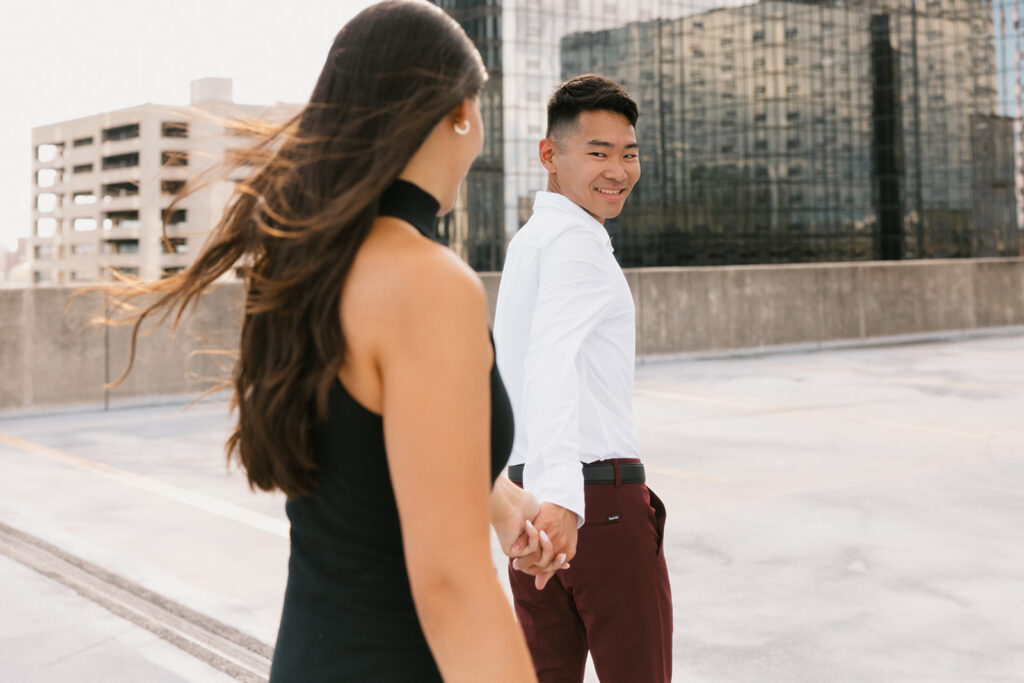 the engaged couple walking along the rooftop for engagement photos