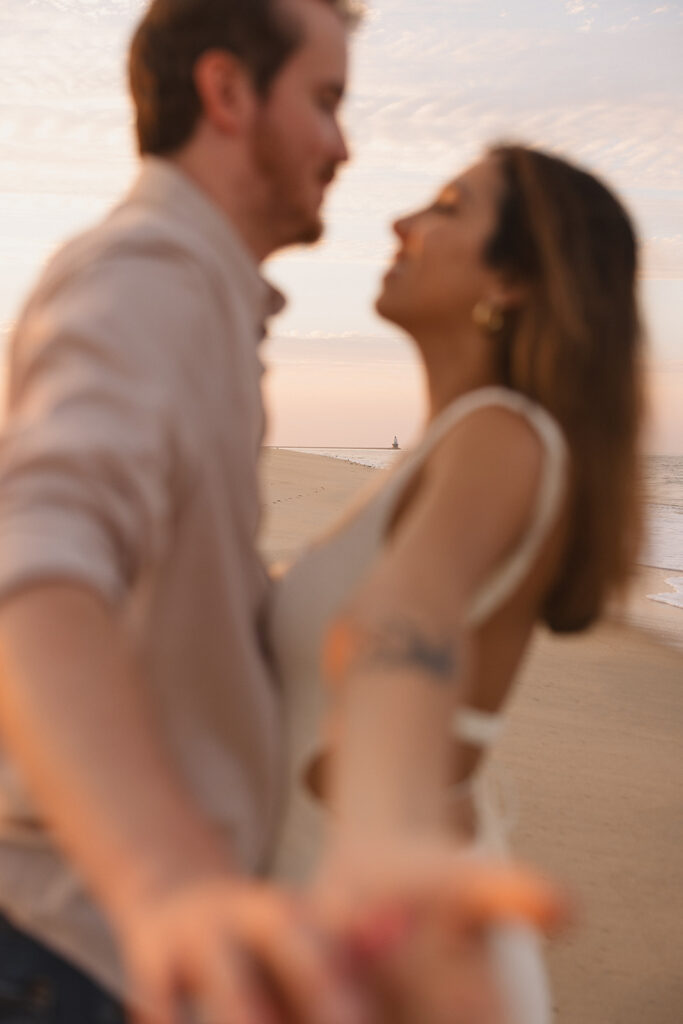 the engaged couple on the beach for engagement photos during sunset