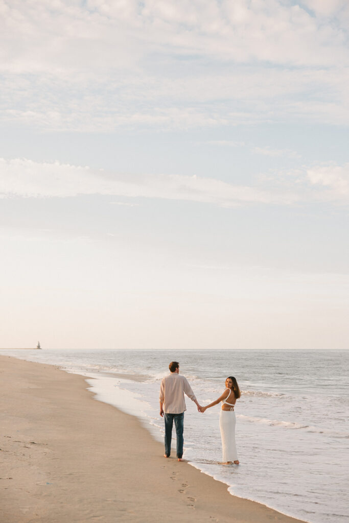 the couple walking along the shore during their east coast beach engagement photos