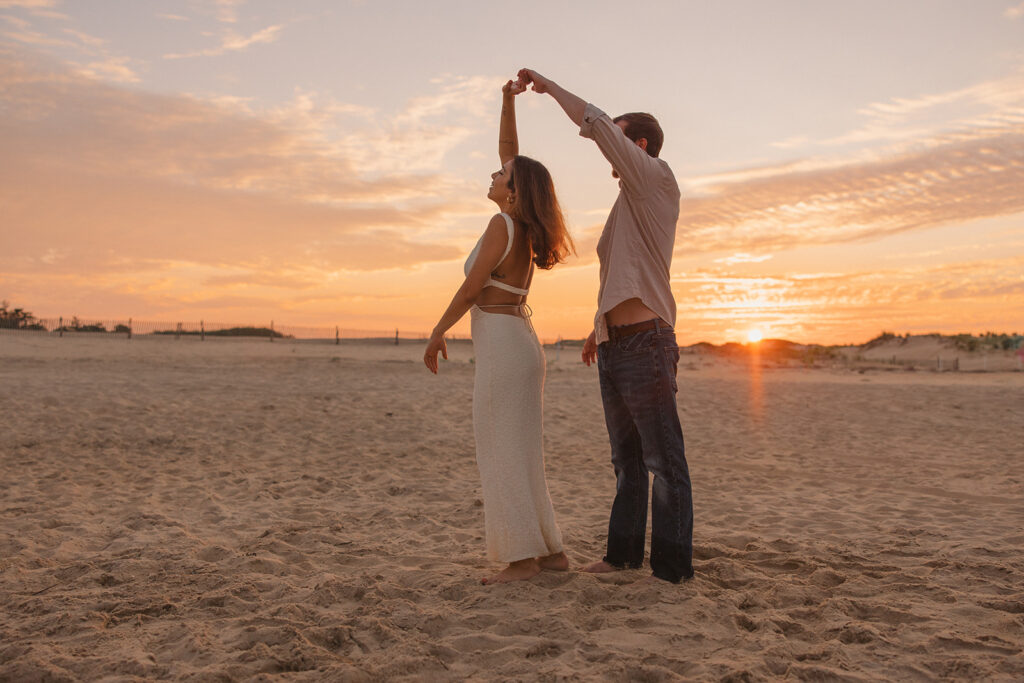 the engaged couple dancing during sunset on the beach