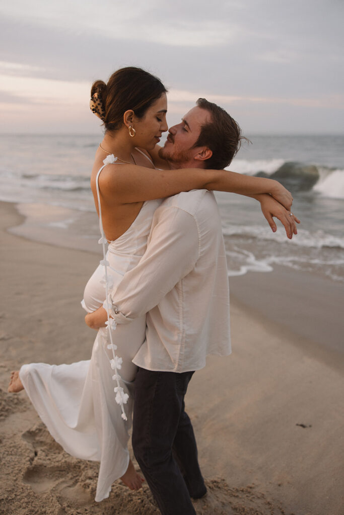 being lifted up by her fiance for timeless beach engagement photos