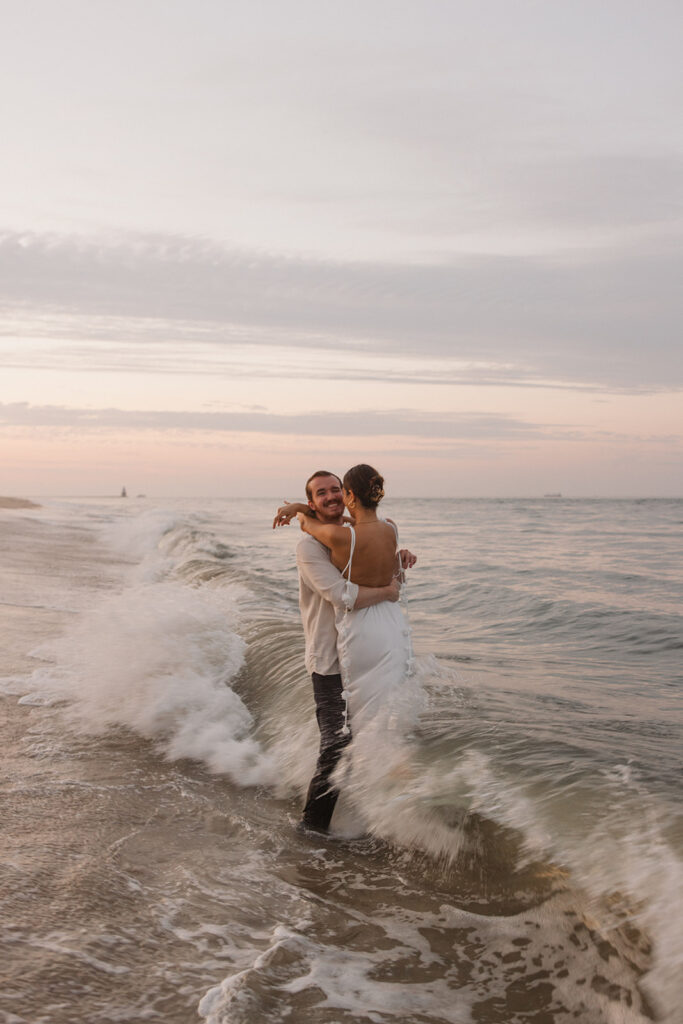 the engaged couple hugging in the waves during their beach engagement photos