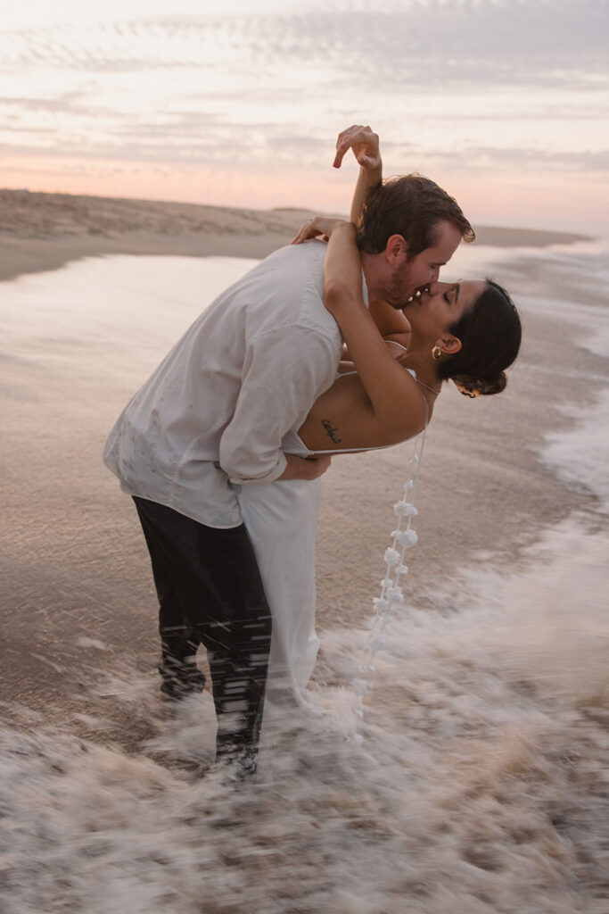 the engaged couple kissing in the water during their perfect beach engagement session 