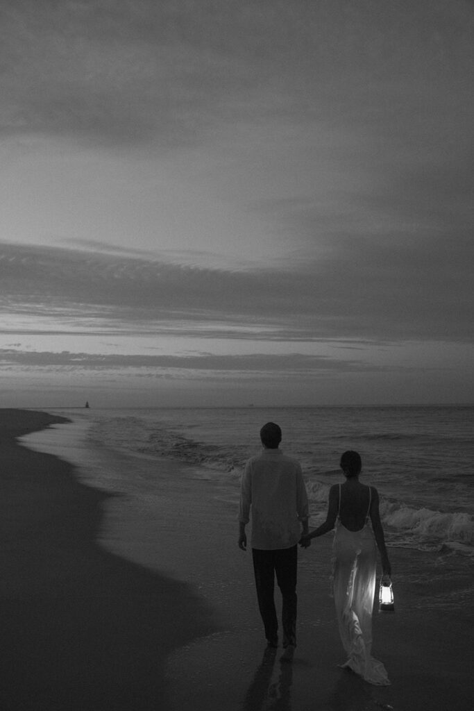 black and white beach engagement photo of the engaged couple holding a lantern on the beach 
