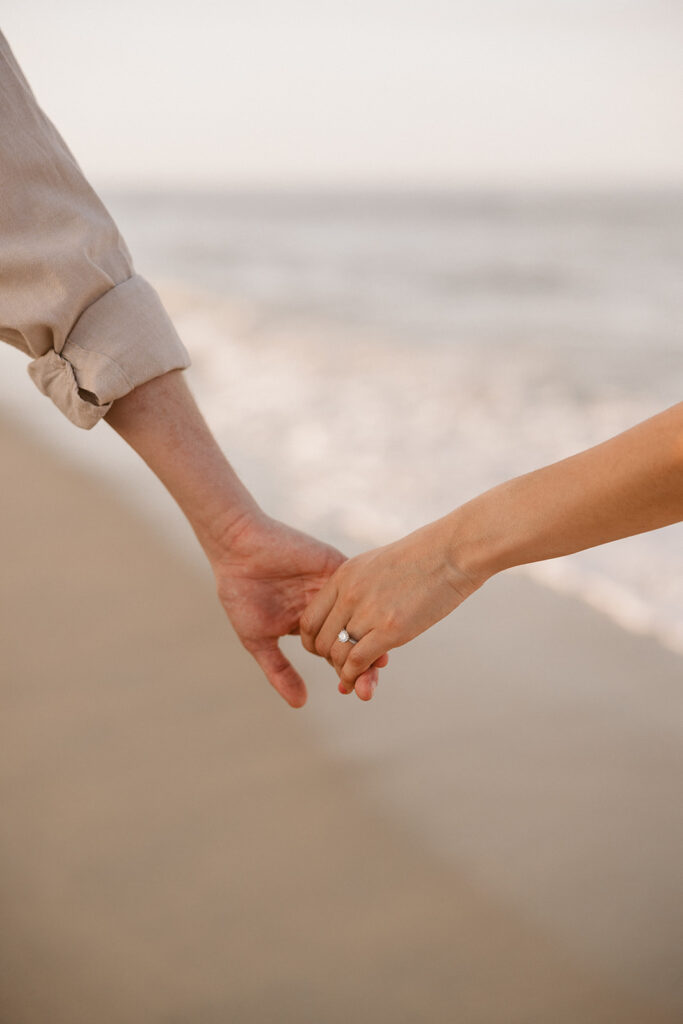 the engaged couple holding hands zoomed in beach engagement photo