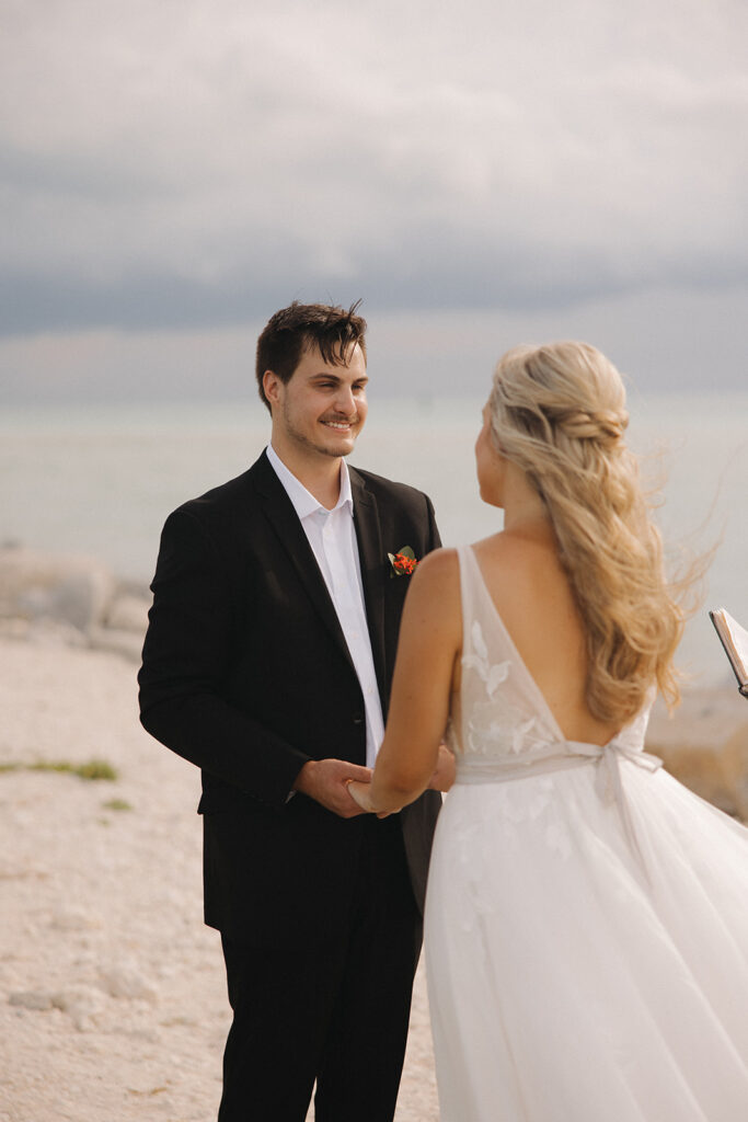 the bride and groom holding hands as they get married on the beach in Florida