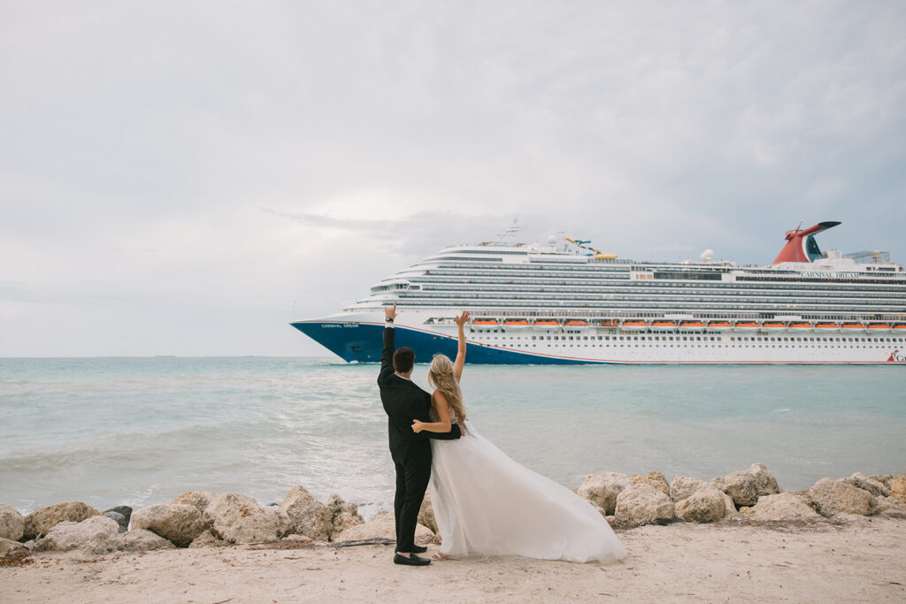 the bride and groom waving to a cruise ship as it passes by