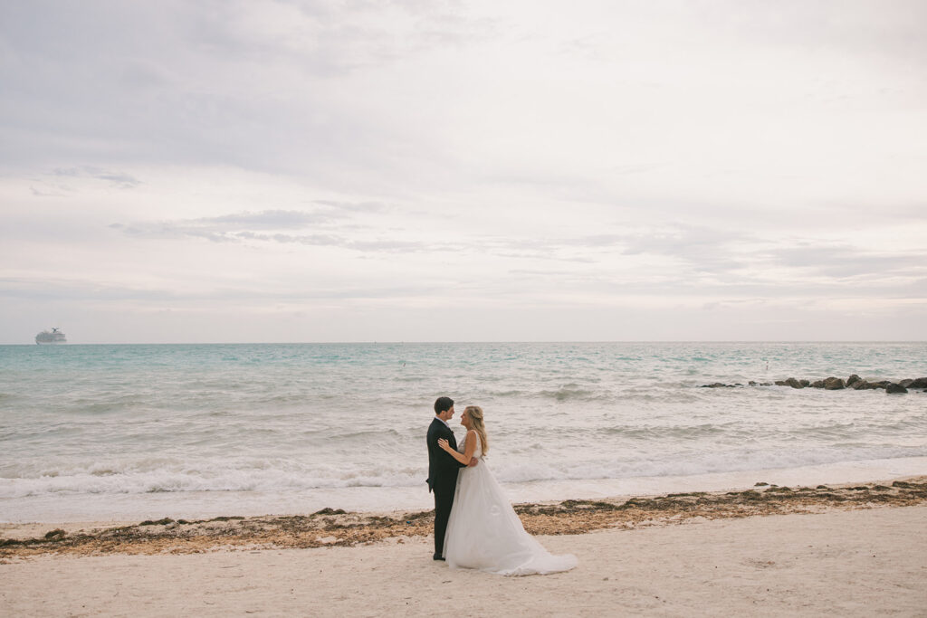 the bride and groom facing one another on the beach in Key West