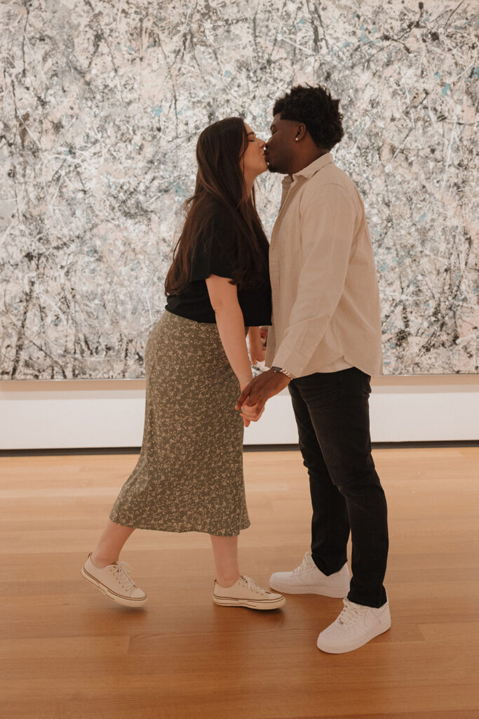 the engaged couple kissing in the art museum