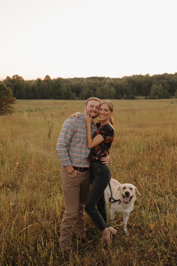 the engaged couple posing together with their dog 