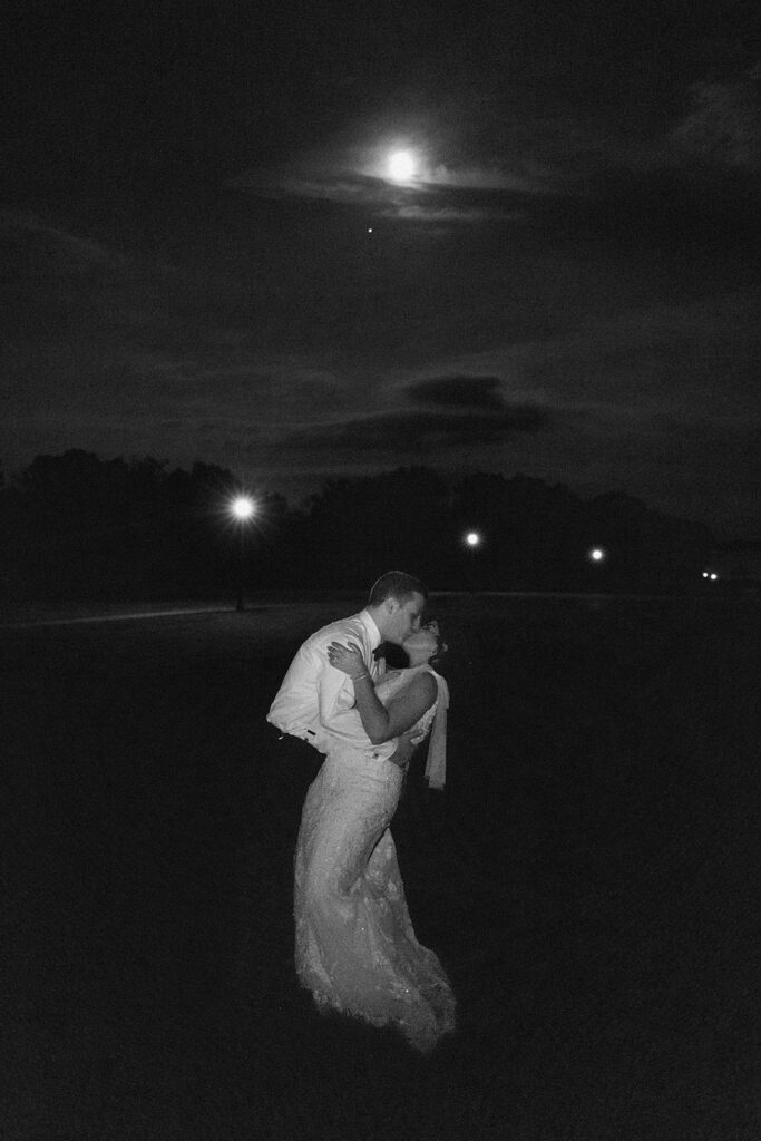 the wedding couple kissing under the full moon
